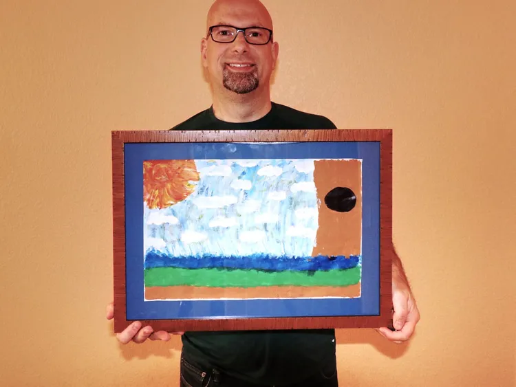 guy holding up a framed painting.