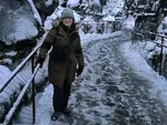Person walking on snowy path through rocky gorge with railings on a winter day.
