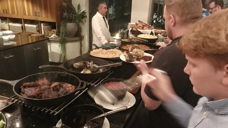 people in front of a kiitchen buffet with a chef serving them.