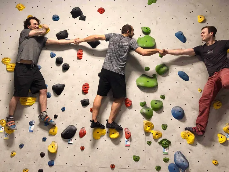 2 guys rock climbing inside a gym.